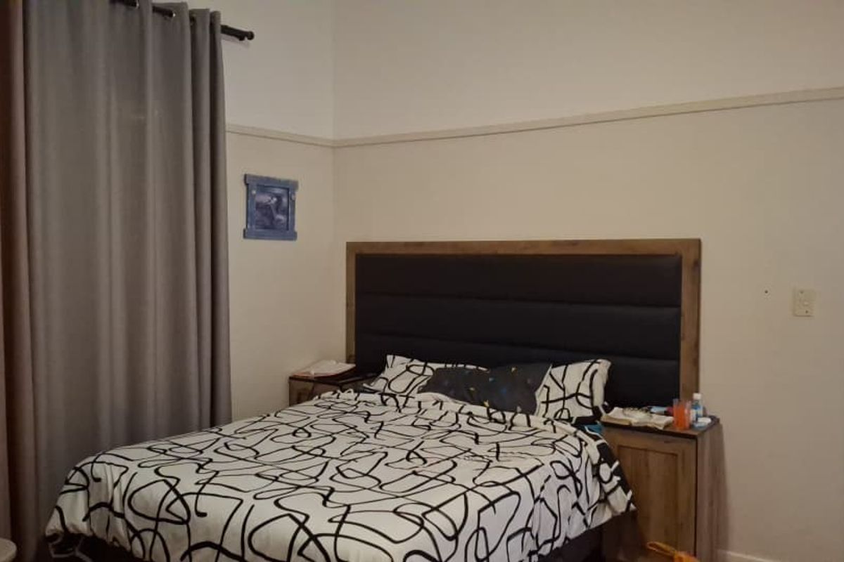 A bedroom featuring high ceilings, a picture rail, and a doorway leading to an adjacent room.