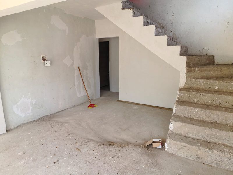 An unfinished interior space featuring a raw concrete staircase and unplastered walls, offering a blank canvas for renovation and custom interior design.