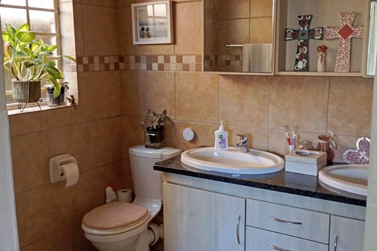 A functional bathroom featuring a dual vanity with granite countertop, built-in cabinetry, a toilet, and tiled walls and flooring.