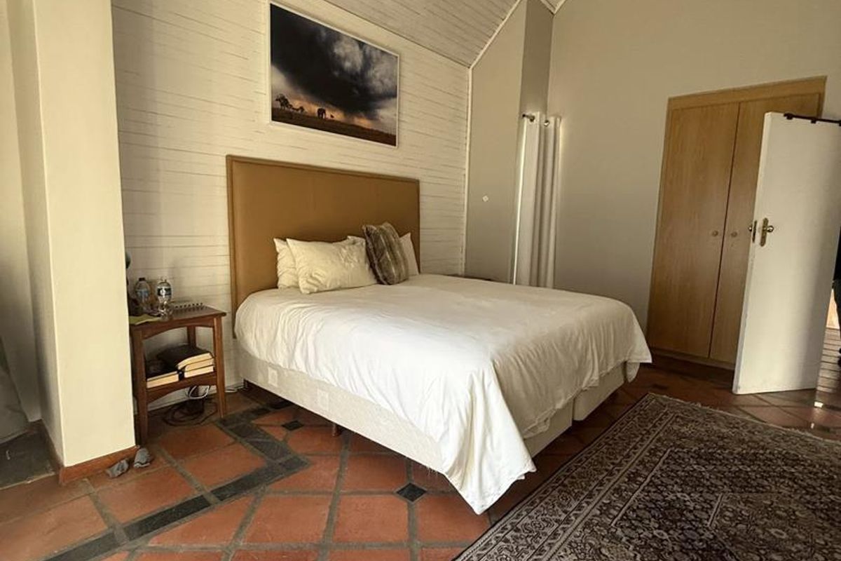 Spacious bedroom featuring high vaulted timber ceilings, terracotta tiled flooring, and built-in wooden cabinetry.