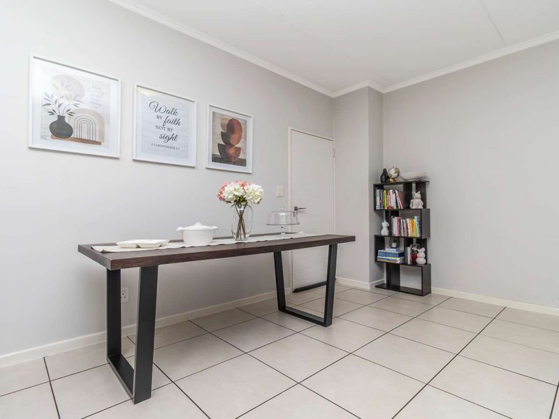 A bright and neutral dining area featuring clean tiled flooring and coved ceiling details, providing a versatile space for meals and entertaining.