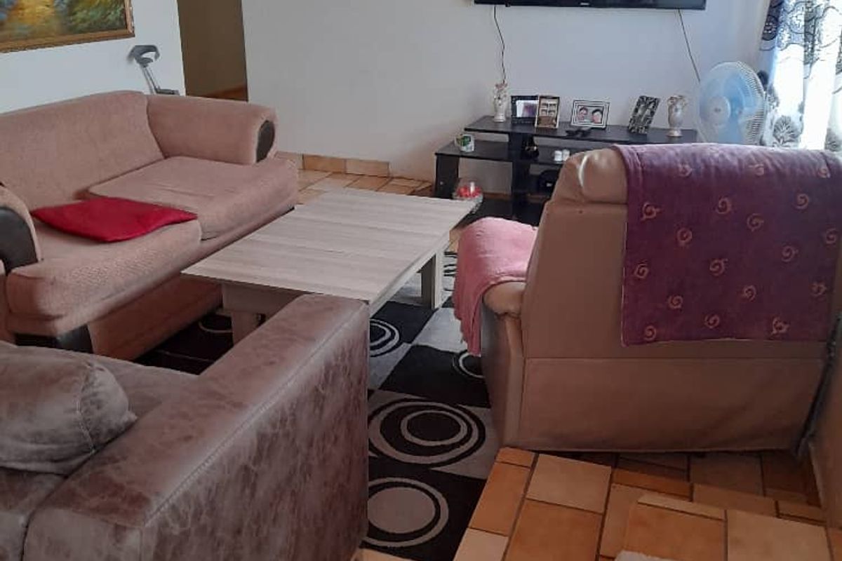 A cozy living room featuring tiled flooring and a wall-mounted television, providing a comfortable space for relaxation.
