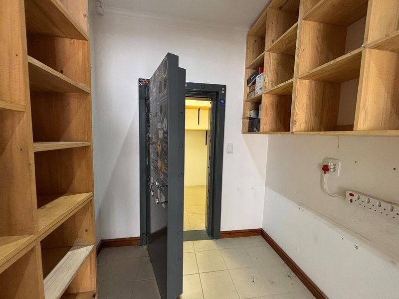 A utility or storage room featuring built-in wooden shelving and a secure heavy-duty steel vault door, providing a dedicated space for secure storage.