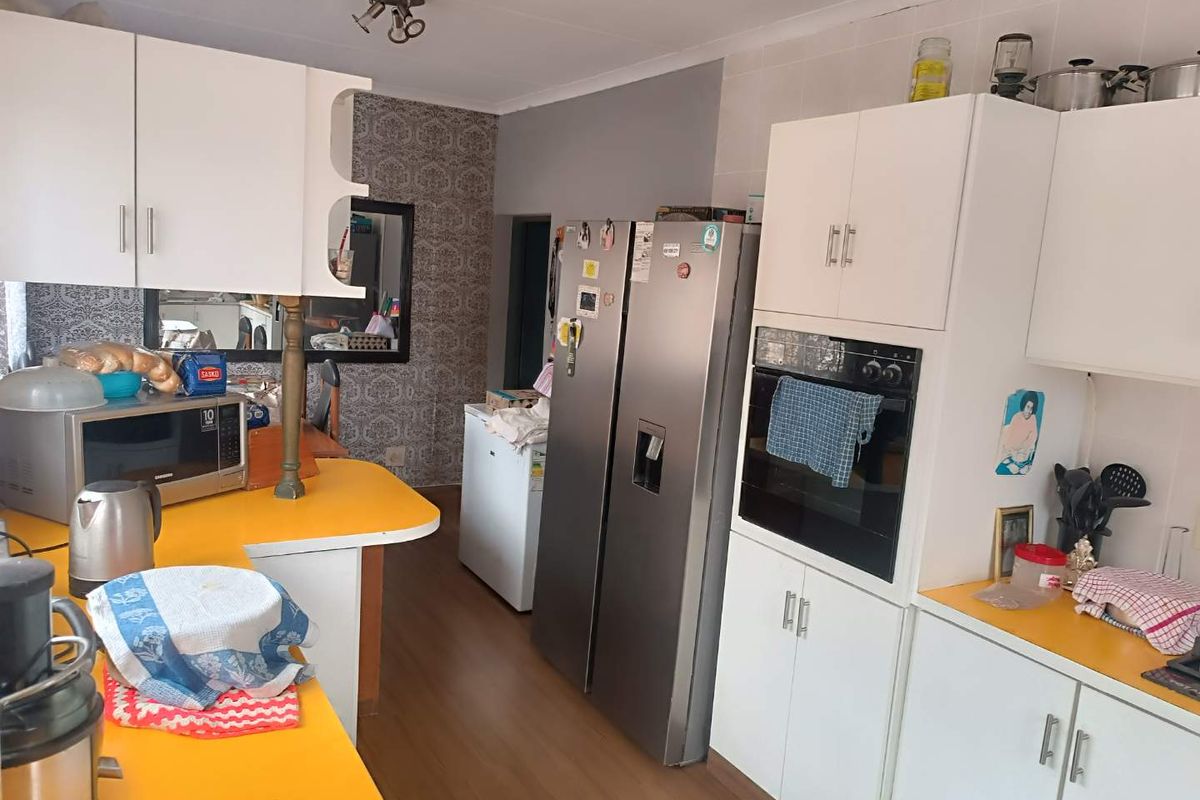 A functional kitchen featuring white cabinetry, yellow laminate countertops, and a built-in oven, offering a practical layout for daily meal preparation.