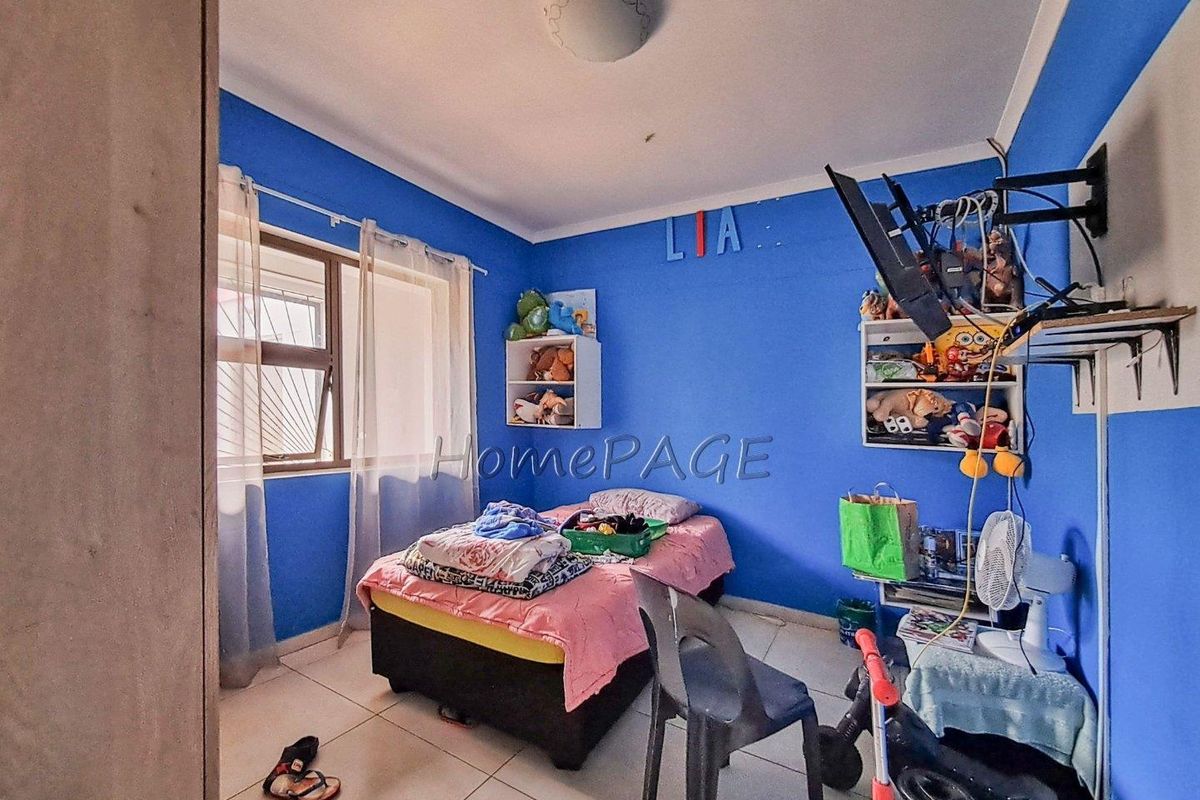 A bedroom featuring tiled flooring, a window with security bars, and a ceiling-mounted light fixture.