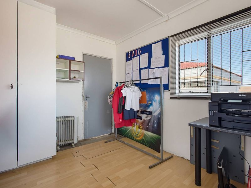 A bedroom featuring laminate flooring, built-in wardrobe storage, and security bars on the window.