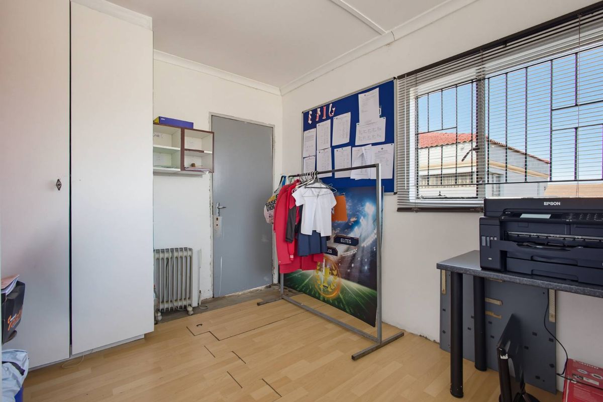 A bedroom featuring laminate flooring, built-in wardrobe storage, and security bars on the window.