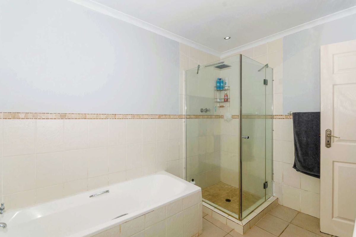 A functional bathroom featuring a built-in bathtub and a separate glass-enclosed shower with tiled walls and flooring.