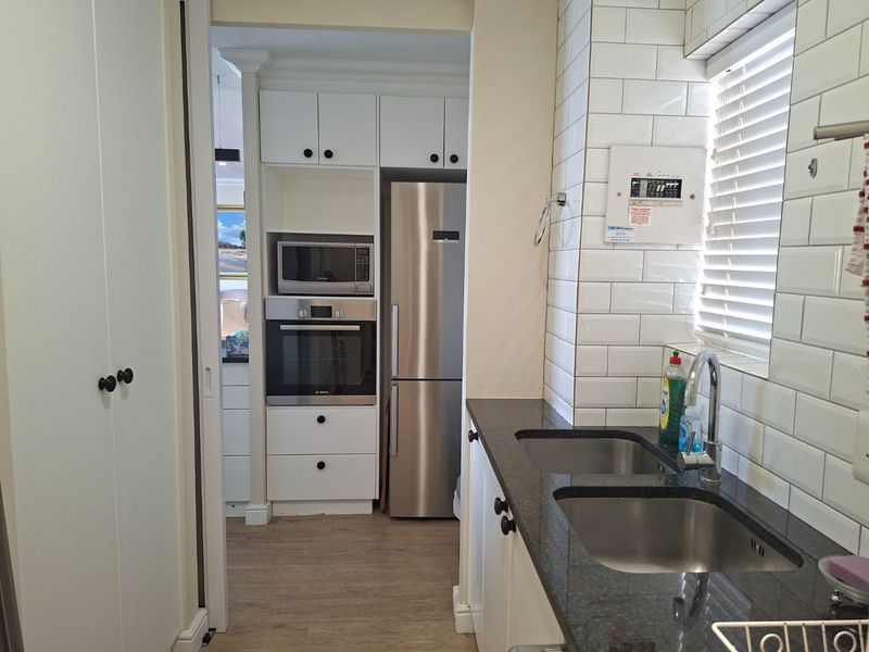 A functional kitchen featuring white cabinetry, subway tile backsplash, granite countertops, a double stainless steel sink, and integrated oven and microwave appliances.