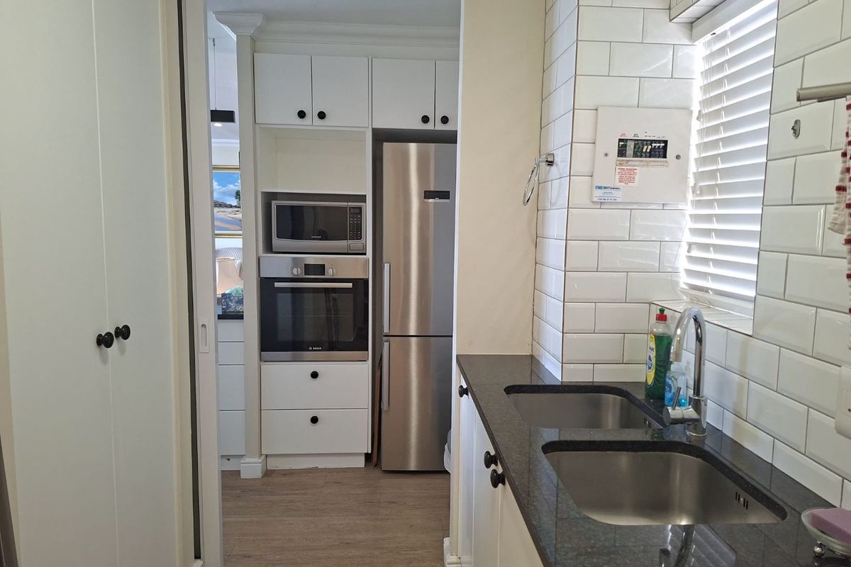 A functional kitchen featuring white cabinetry, subway tile backsplash, granite countertops, a double stainless steel sink, and integrated oven and microwave appliances.
