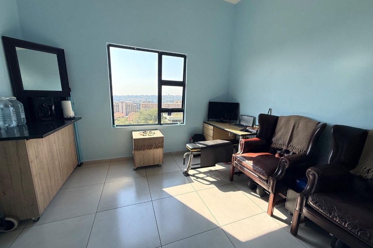 A bright bedroom featuring large windows with city views, tiled flooring, and built-in cabinetry, offering a functional space with natural light.