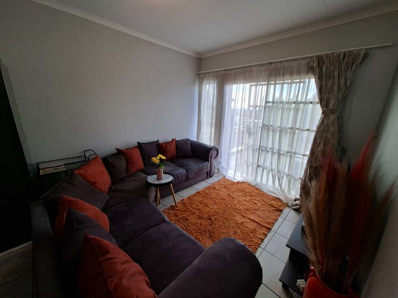 A comfortable living room featuring tiled flooring and a large sliding glass door that provides access to an outdoor area.