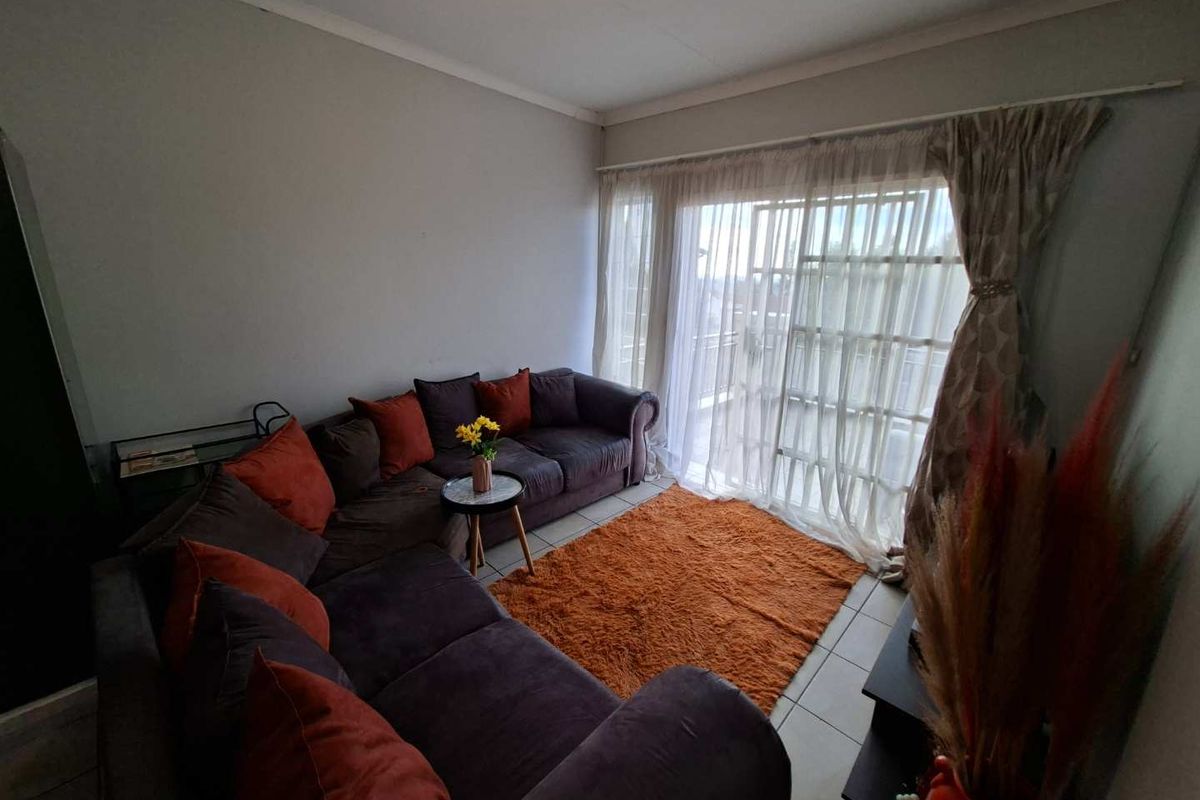 A comfortable living room featuring tiled flooring and a large sliding glass door that provides access to an outdoor area.