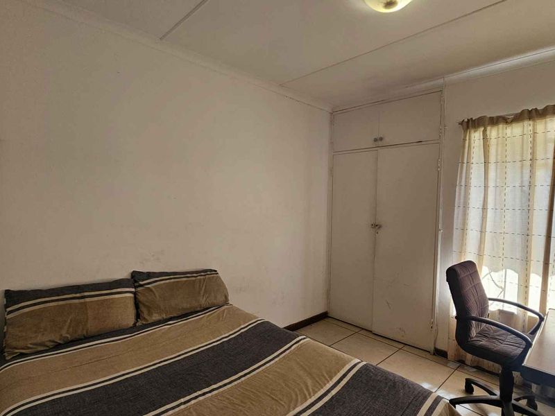 A functional bedroom featuring tiled flooring and a built-in wardrobe, offering a blank canvas for potential cosmetic updates and interior design improvements.