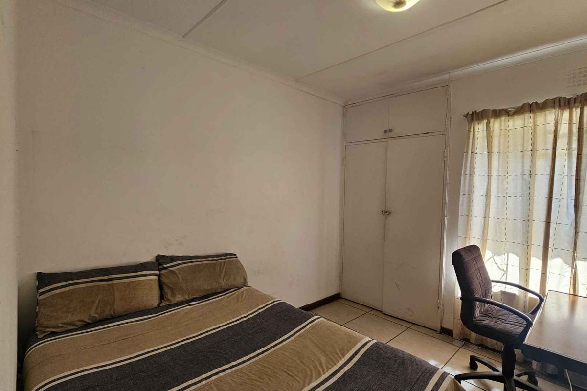 A functional bedroom featuring tiled flooring and a built-in wardrobe, offering a blank canvas for potential cosmetic updates and interior design improvements.