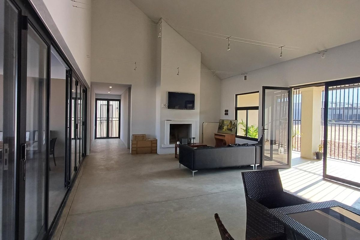 Spacious open-plan living area featuring high vaulted ceilings, a central fireplace, and large sliding glass doors providing ample natural light and outdoor access.
