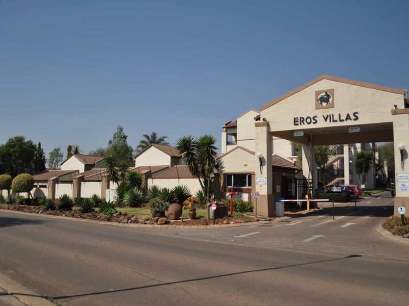 The entrance to Eros Villas apartment complex, featuring a secure gatehouse, boom gate access, and well-maintained perimeter walls.