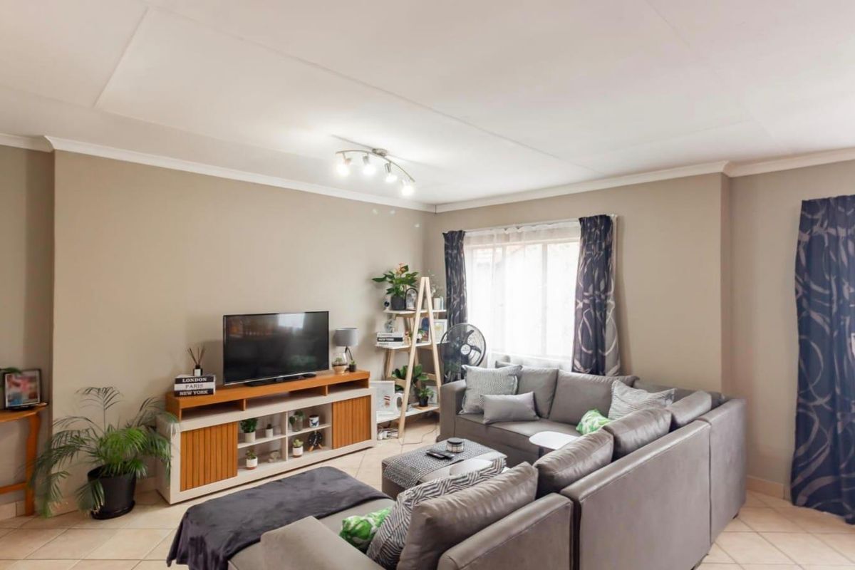 A well-maintained living room featuring neutral wall tones, tiled flooring, and classic ceiling coving, providing a comfortable and inviting space.