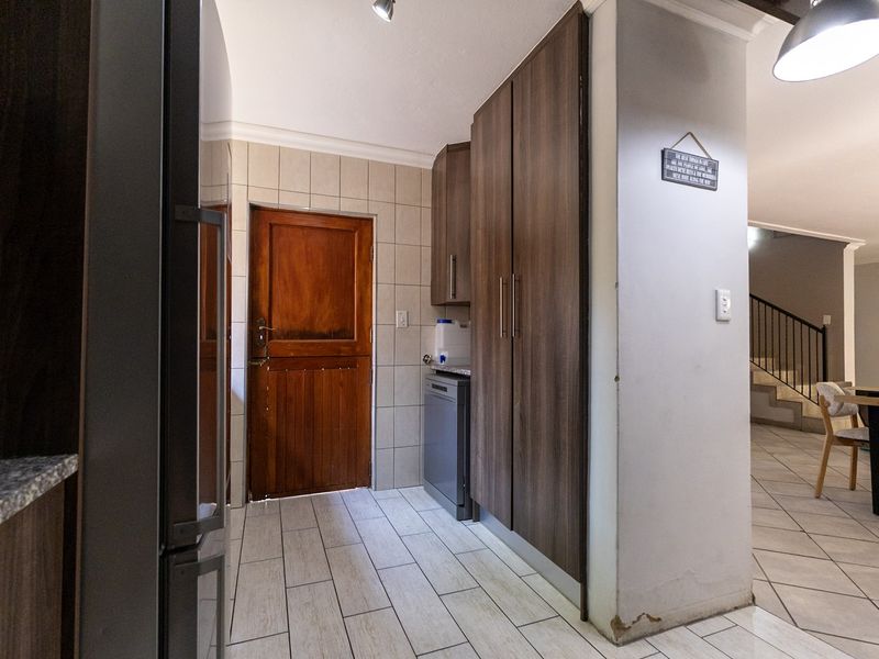 A functional scullery area featuring built-in cabinetry, tiled flooring, and a timber door, providing convenient additional prep and storage space.
