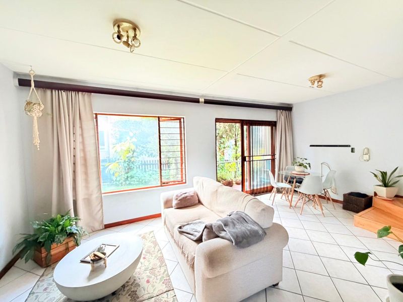 Open plan living and dining area featuring tiled flooring, large windows with security bars, and sliding door access to the outdoor space.