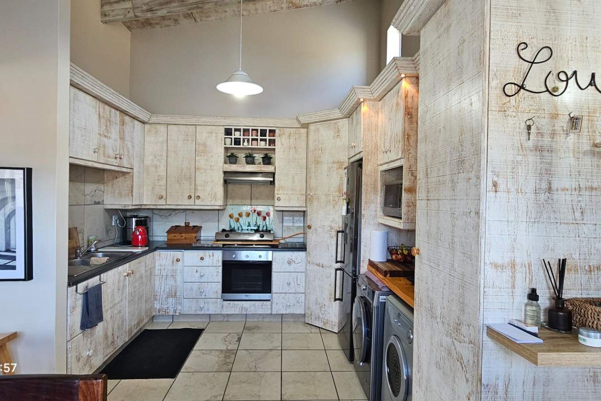 Kitchen featuring rustic distressed-finish cabinetry, built-in oven and hob, tiled flooring, and exposed ceiling beams, offering a unique character-filled cooking space.