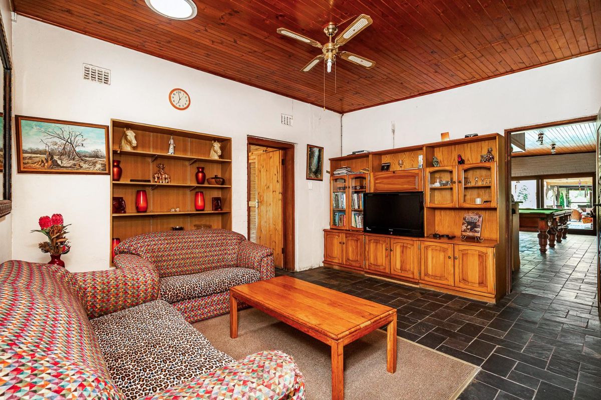 Living room featuring a timber tongue and groove ceiling, slate tile flooring, and built-in timber cabinetry with integrated shelving and storage.
