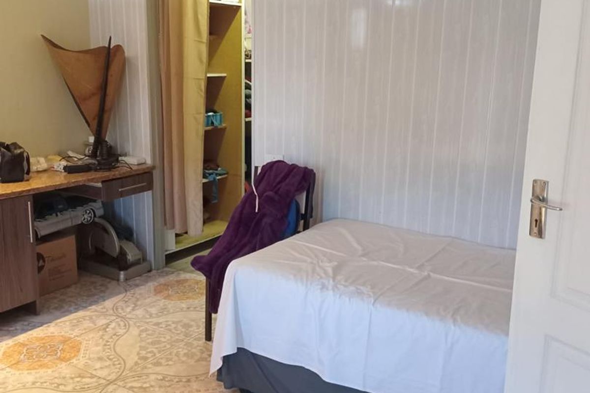 A bedroom featuring patterned floor tiles, wood-look wall paneling, and an integrated storage closet area.