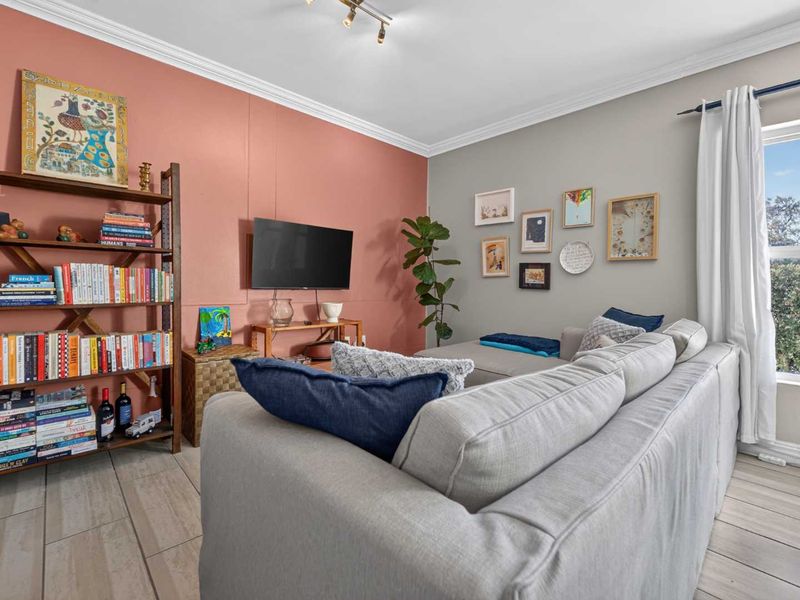 A comfortable living room featuring tiled flooring, crown molding, and a feature wall, offering a bright and inviting space.