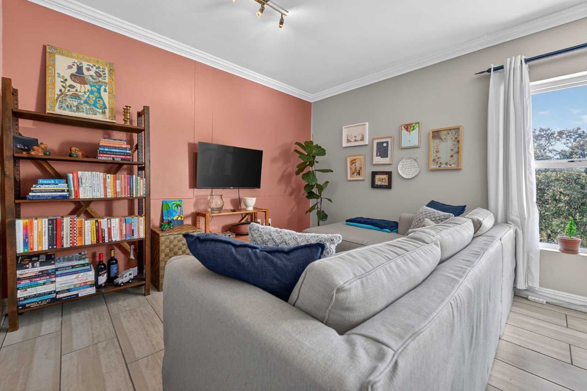 A comfortable living room featuring tiled flooring, crown molding, and a feature wall, offering a bright and inviting space.