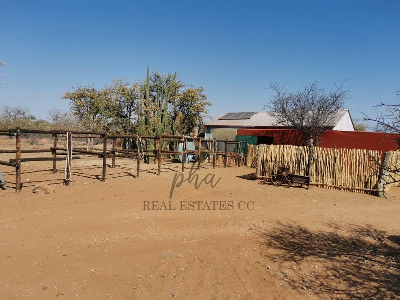 Outdoor farm area featuring timber post fencing, a structure with a corrugated metal roof, and installed solar panels.
