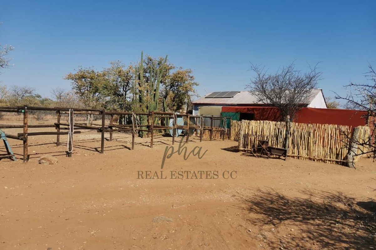 Outdoor farm area featuring timber post fencing, a structure with a corrugated metal roof, and installed solar panels.