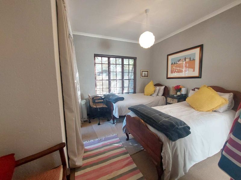 A bedroom featuring carpeted flooring, a window with wooden blinds, and a central ceiling light fixture.