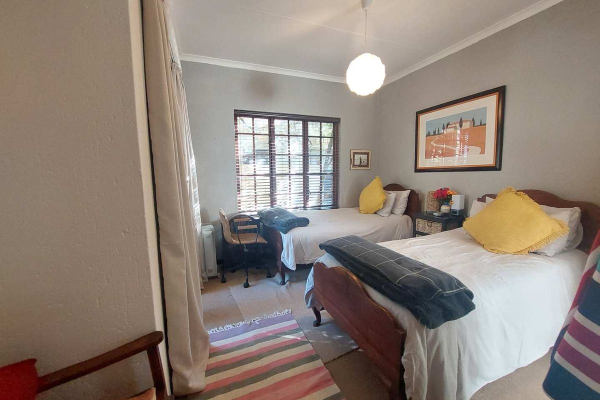 A bedroom featuring carpeted flooring, a window with wooden blinds, and a central ceiling light fixture.