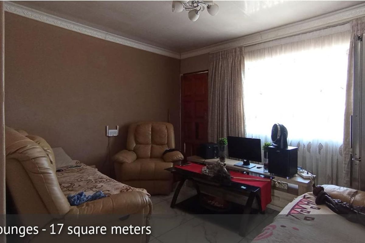 A 17 square meter living room featuring tiled flooring, crown molding, and a large window with curtains.
