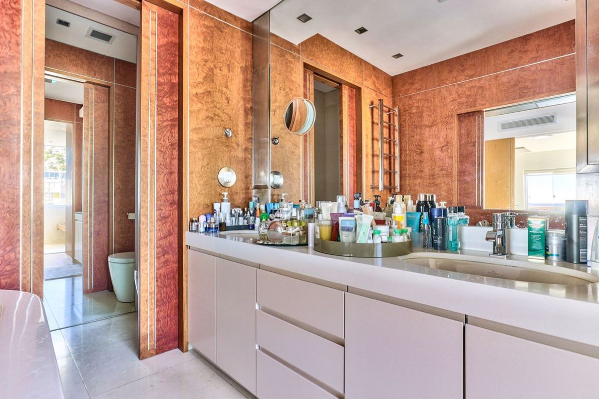 A well-appointed bathroom featuring a double vanity with integrated sinks, extensive wood veneer wall paneling, and a large mirror.
