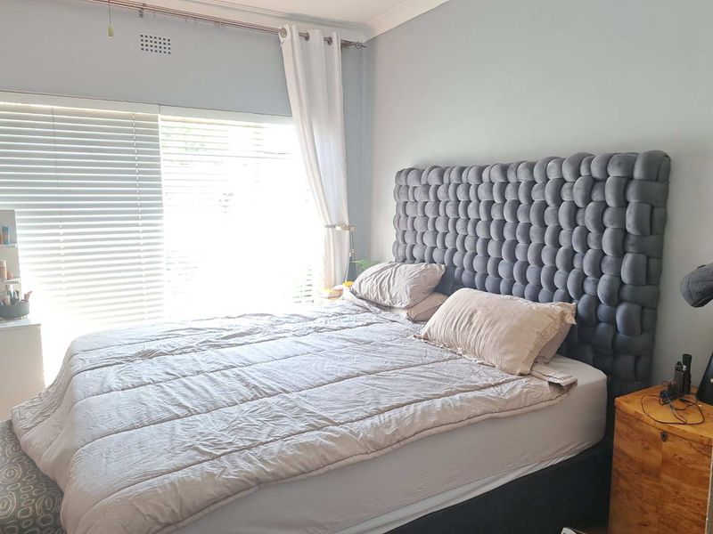 A well-lit bedroom featuring neutral wall tones, venetian blinds, and coving detail, providing a comfortable and functional sleeping space.