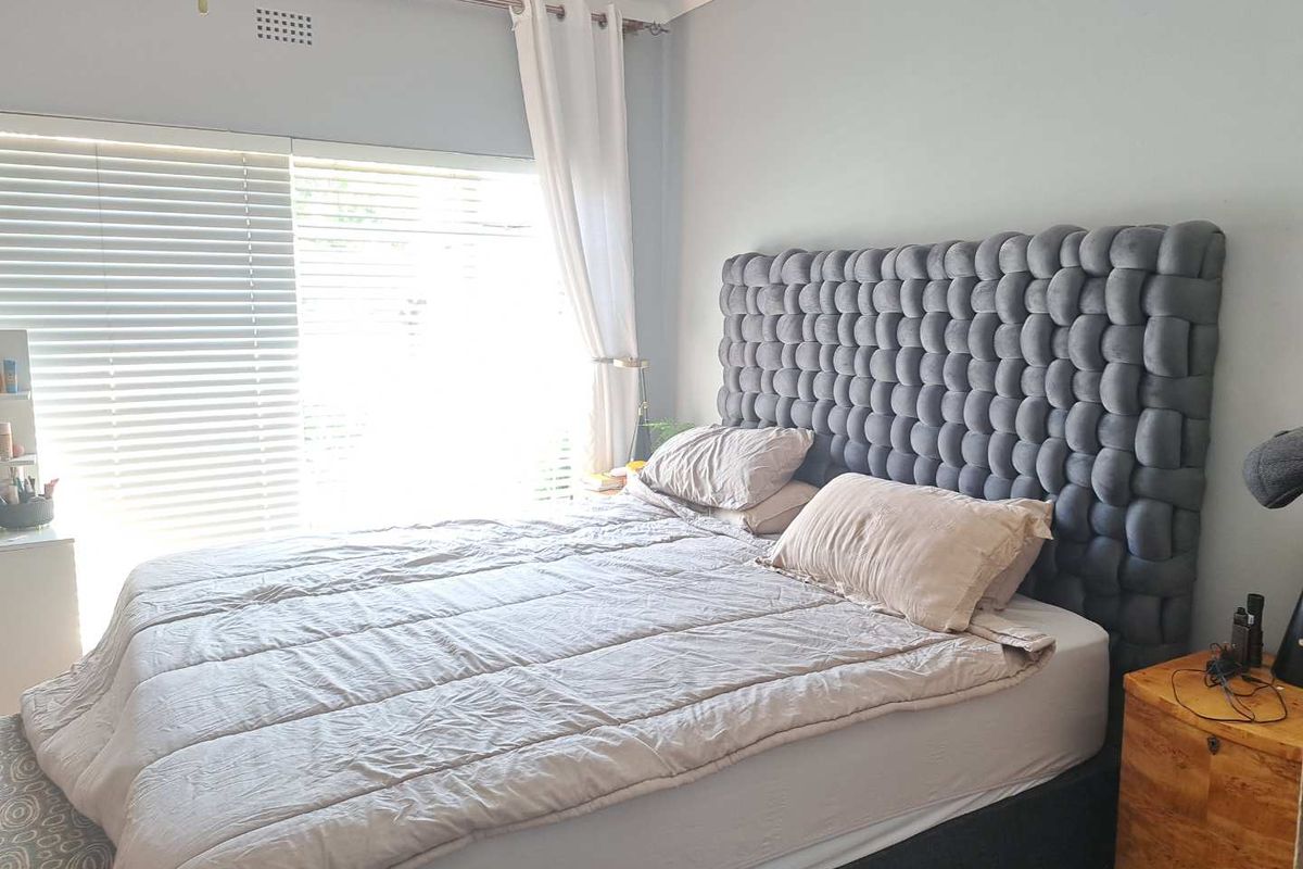 A well-lit bedroom featuring neutral wall tones, venetian blinds, and coving detail, providing a comfortable and functional sleeping space.