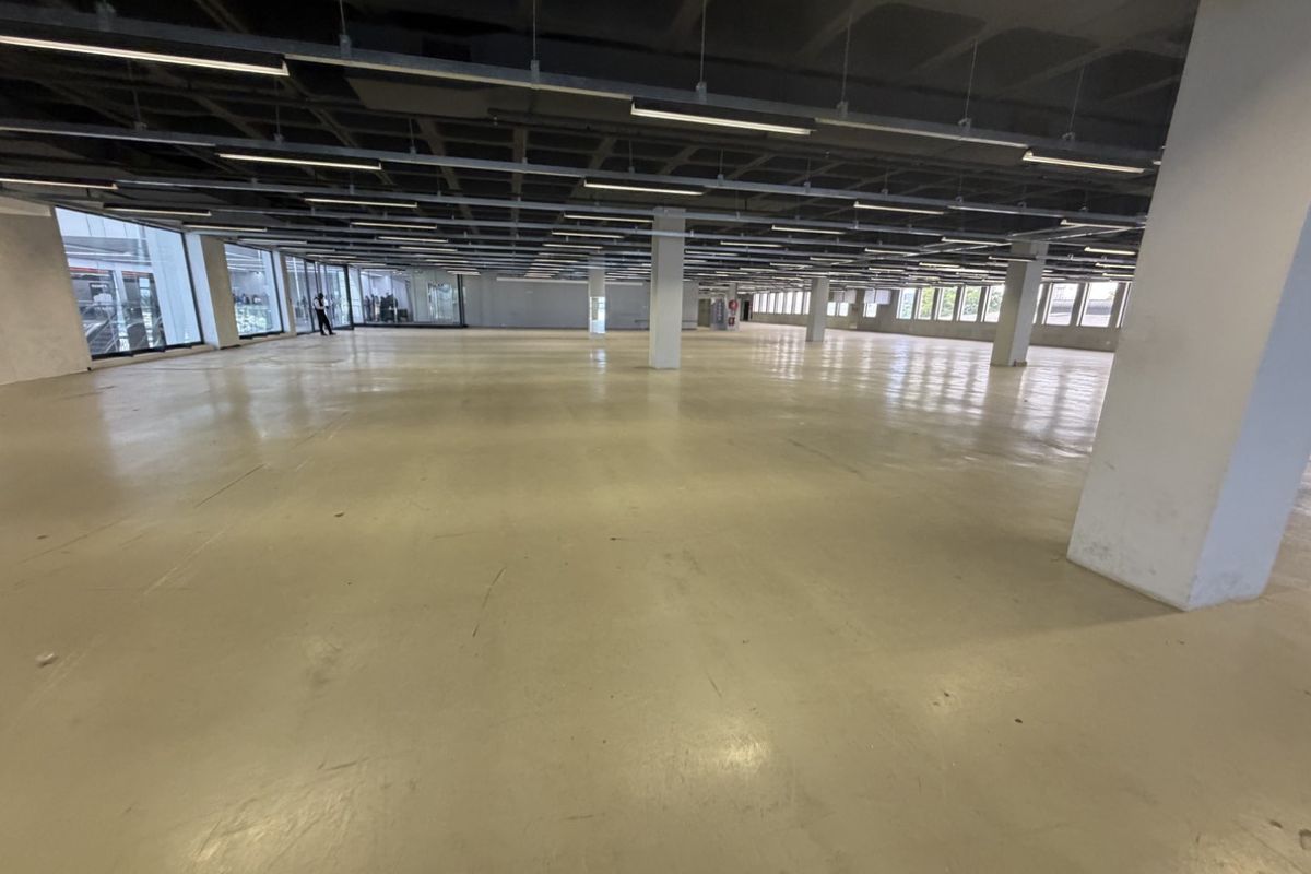 Expansive open-plan industrial office space featuring high exposed waffle slab ceilings, polished concrete floors, and abundant natural light from perimeter windows.