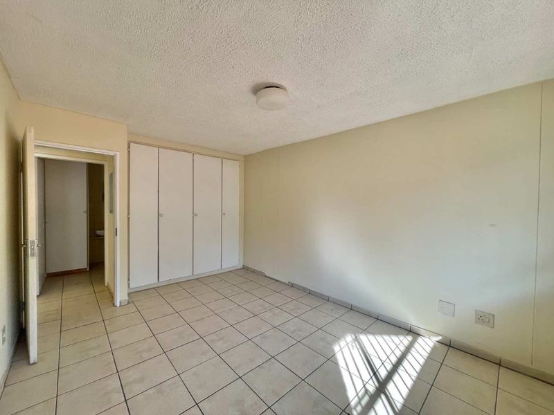 An empty bedroom featuring tiled flooring and built-in cupboards, offering a blank canvas for personalization.
