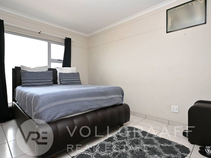 A standard bedroom featuring tiled flooring, a sliding window, and neutral wall finishes, providing a functional space for rest.