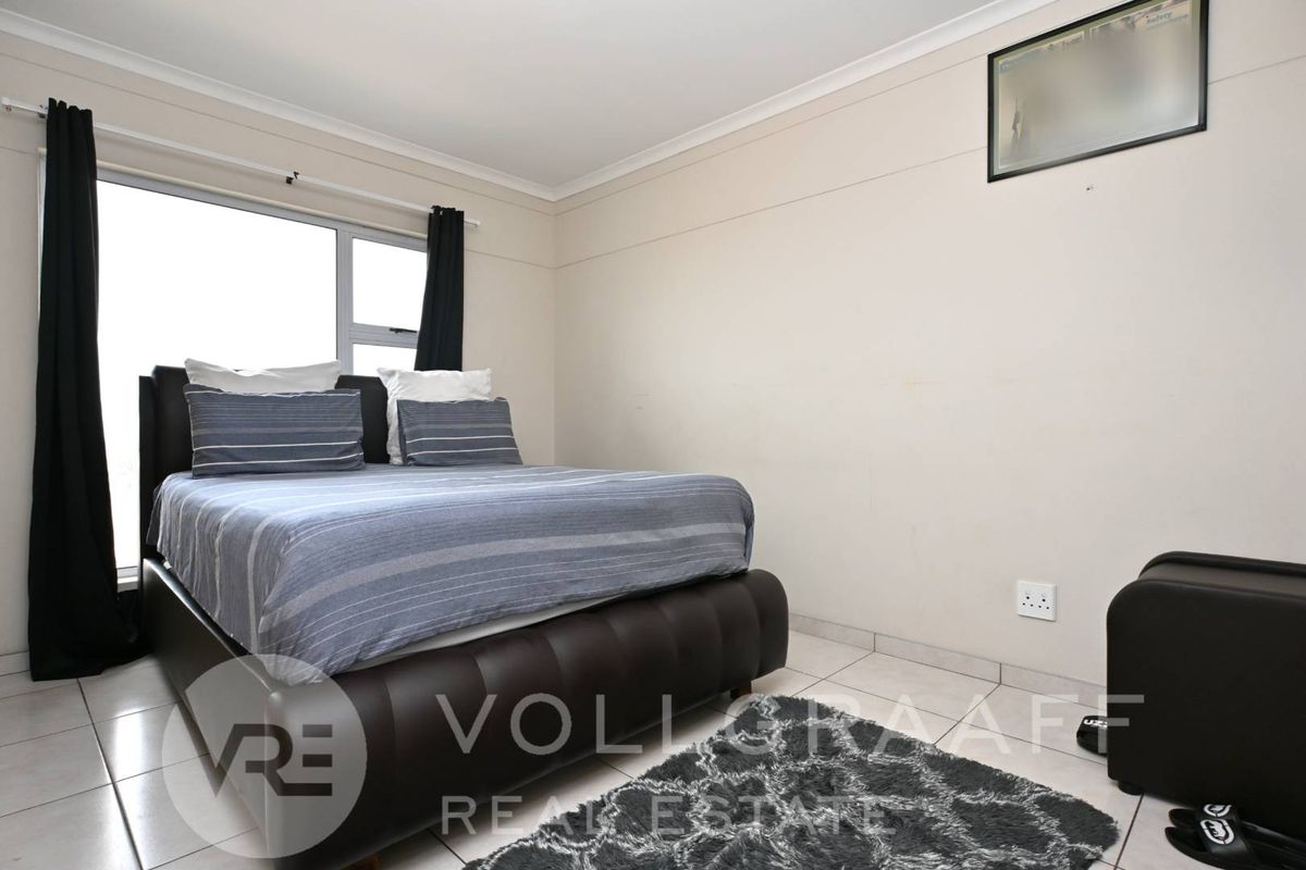 A standard bedroom featuring tiled flooring, a sliding window, and neutral wall finishes, providing a functional space for rest.