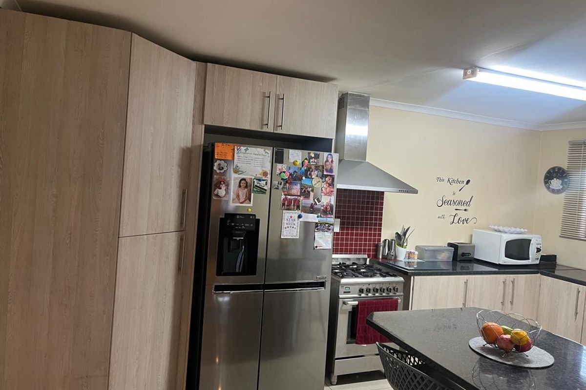 A functional kitchen featuring light wood-grain cabinetry, granite countertops, a stainless steel gas hob with extractor fan, and a tiled splashback.