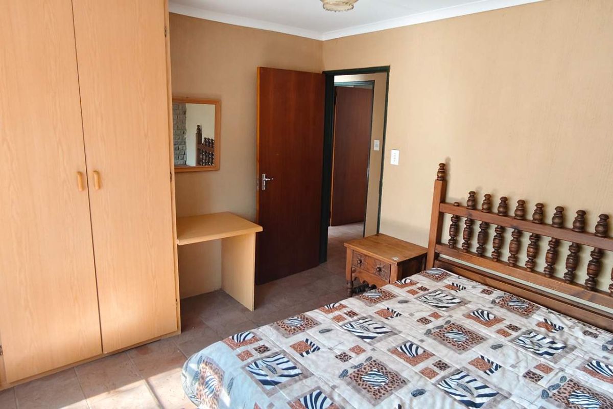 A bedroom featuring built-in wooden wardrobes, a matching built-in vanity, and tiled flooring.