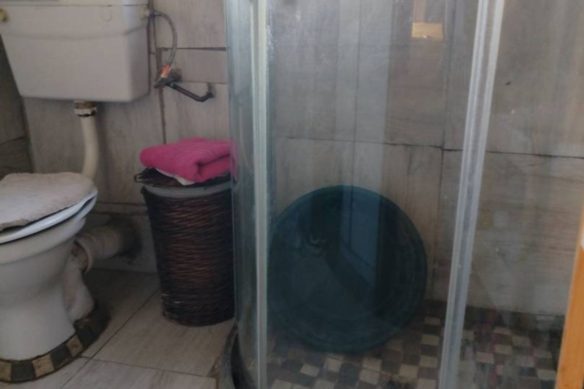 A compact bathroom featuring a corner shower enclosure and standard toilet with tiled finishes throughout.