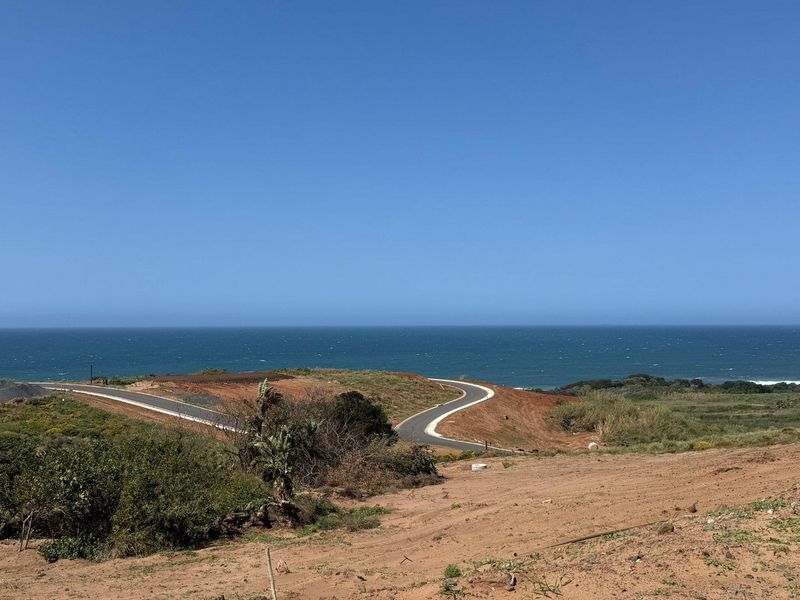 A scenic view of the coastline featuring a paved access road winding through the vacant residential land.