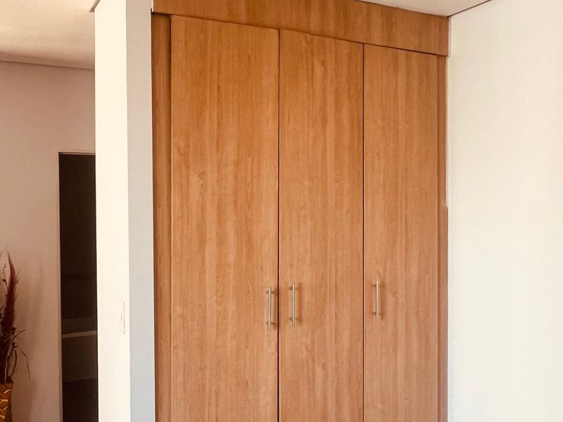 A bedroom featuring a well-maintained, full-height built-in wooden wardrobe with modern metal handles.