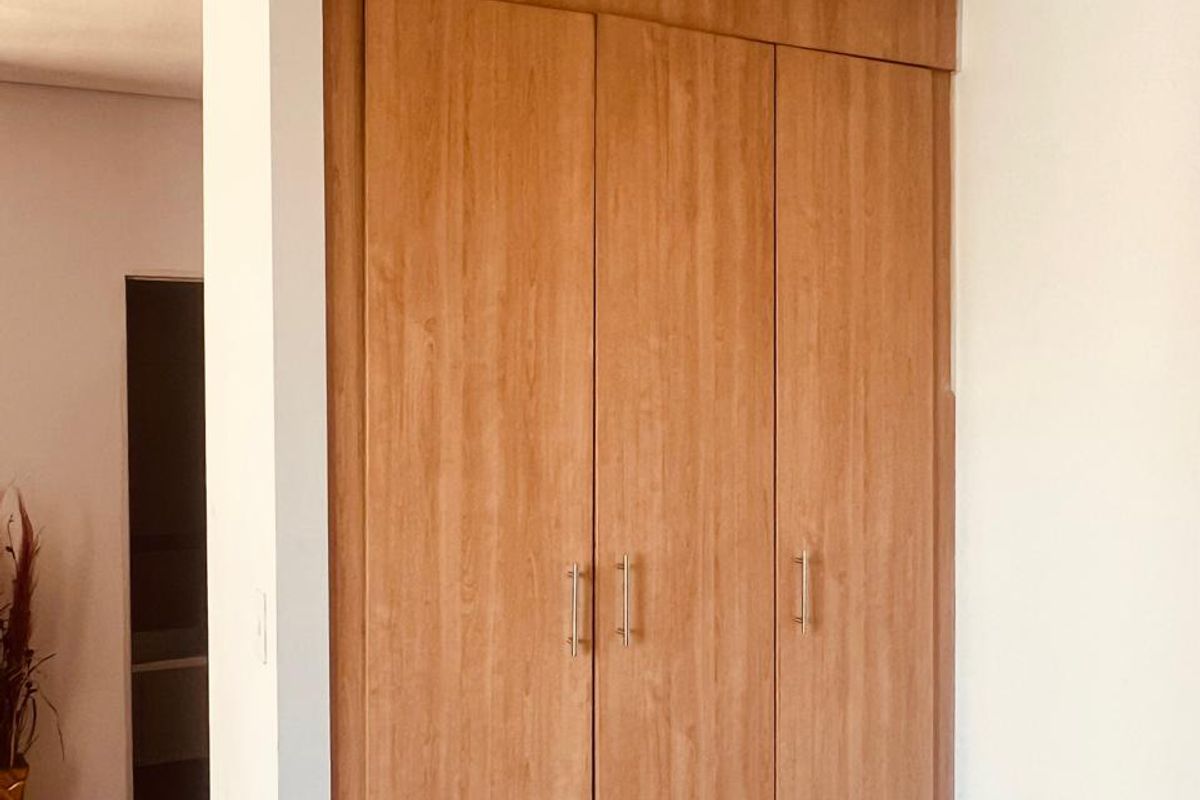 A bedroom featuring a well-maintained, full-height built-in wooden wardrobe with modern metal handles.