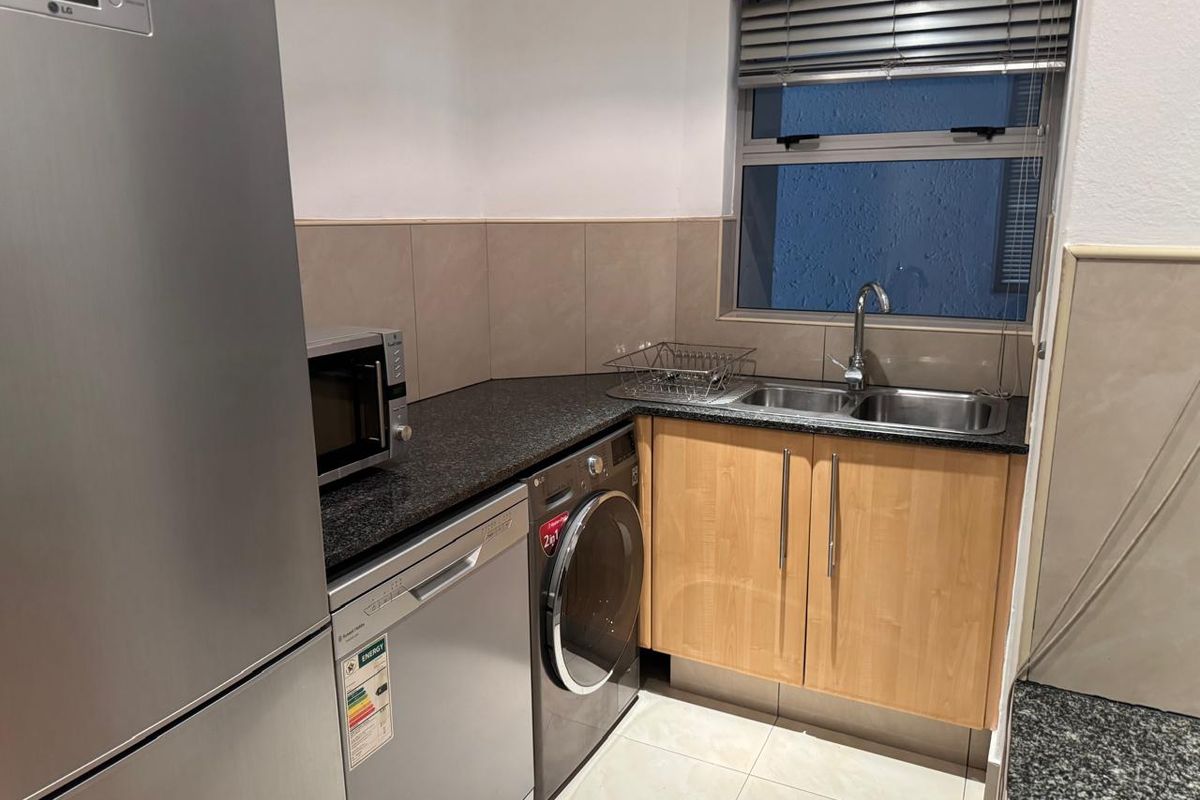 A functional kitchen area featuring granite countertops, double sink, built-in cabinetry, and tiled finishes, providing a practical space for daily utility.