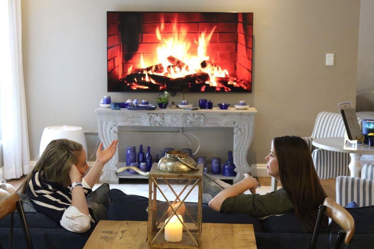 A cozy living room area featuring a wall-mounted television displaying a fireplace, set above a decorative console table.