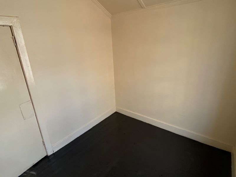 An empty bedroom featuring dark painted timber flooring and neutral wall tones, providing a blank canvas for potential interior design updates.